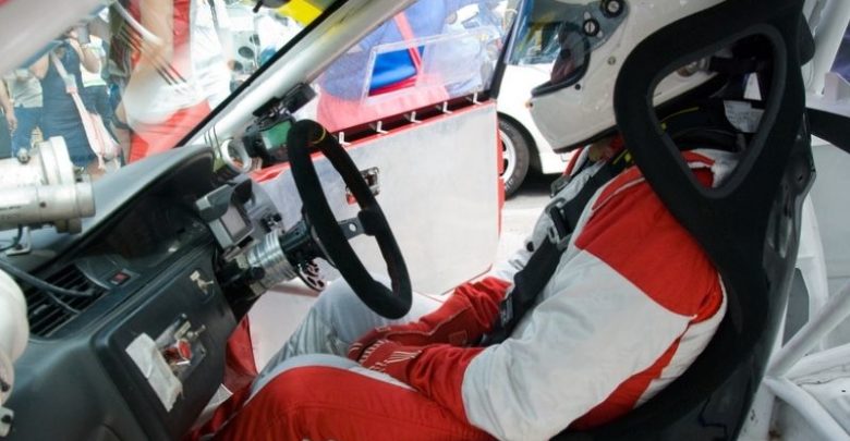 race car driver in full gear sitting inside car