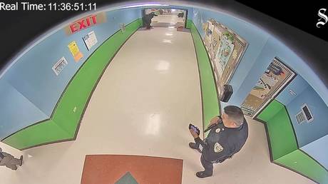 A police officer checks his phone during the May 24 mass shooting at Robb Elementary School in Uvalde, Texas, as seen in newly released security footage.