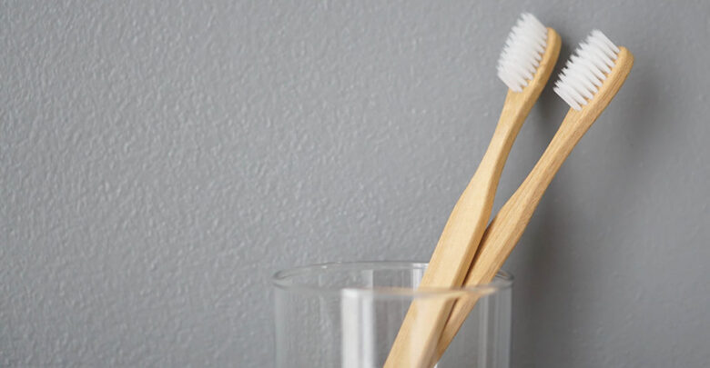 Close up wooden toothbrush in glass with grey background, selective focus