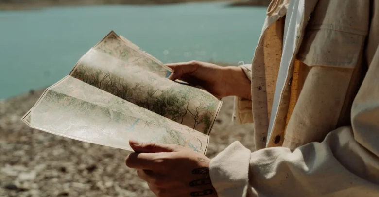 A traveler holding a map beside a lakeK